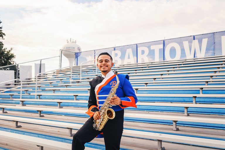 high school senior band member posing on the bleachers with his saxophone in bartow, florida