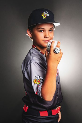 young baseball player holing a baseball and wearing his championship ring - taken in the bc visuals bartow studio using dramatic smoke and lights