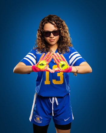 female flag football player posing on simple studio background