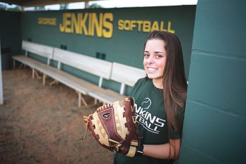 high school senior softball player in the dugout using natural setting