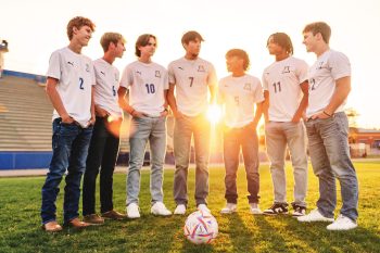 group of senior soccer players posing on their home field at sunset