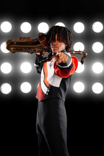 Lakeland high school marching band student posing with his saxophone on a digital background.