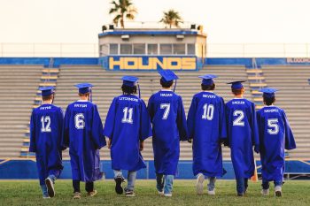 senior soccer players in cap & gowns posing on the auburndale football field