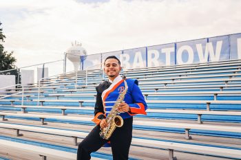 high school senior band member posing on the bleachers with his saxophone in bartow, florida