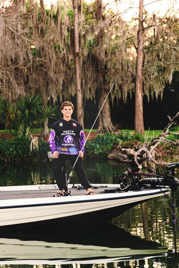 high school fishing team senior portrait on his bass boat on a lake with a fishing pole in lakeland, florida