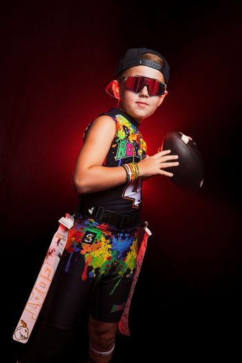 young flag football boy posing with his flags, shades, and ball using dramatic red smoke and light