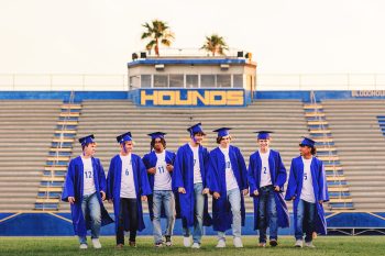 high school senior soccer players dressed in cap & gowns on the soccer field.