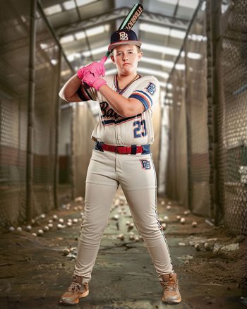 travel ball baseball player posing with a bat in a digital batting cage backdrop