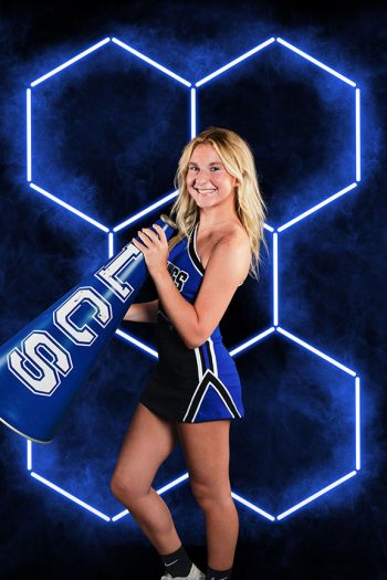 cheerleader posing with megaphone in front of hex light digital background